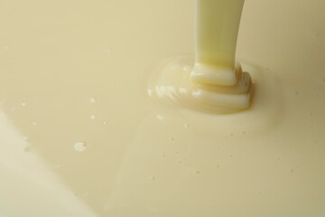 Pouring delicious condensed milk as background, closeup