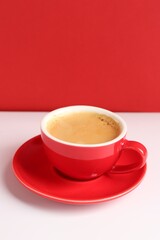 Red cup with coffee on white table