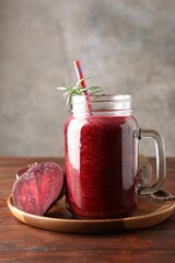 Fresh beetroot smoothie in mason jar and vegetables on wooden table, closeup