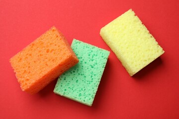 Soft sponges on red background, flat lay. Cleaning tool