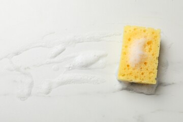 Yellow sponge with foam on white background, top view. Space for text