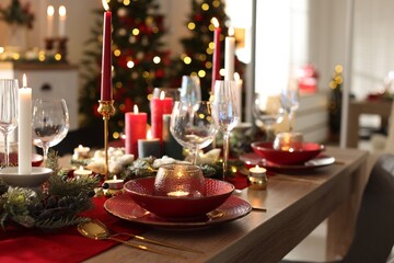 Christmas place setting with festive decor on wooden table in room