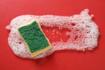 One cleaning sponge and foam on red background, top view. Space for text