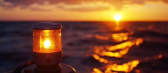 Sunset over the ocean with a lantern glowing in the foreground.