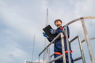 Engineer in Full Safety Gear Climbing a Ladder to Inspect Communication Signals and Industrial Machinery at a High-Risk Transportation Facility