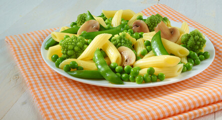 Gemueseteller mit Pasta auf weissem Porzellanteller mit gelb weisser Serviette, Tellergericht, Erbsen, Bohnen,