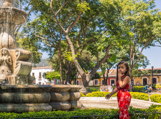 Little girl standing in front of a beautiful colonial fountain, sends a kiss to her mother and she takes a portrait of her as a souvenir.