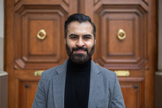 Indian businessman in grey coat in front of wooden door
