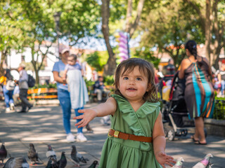 Little girl waits with her arm outstretched and her hand open, for her aunt to give her seeds to...