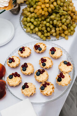 table with desserts. In the foreground is a glass plate with small tartlets