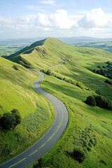 Fototapeta premium Serene winding road through lush green hills under blue skies
