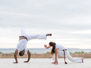 A couple doing capoeira exercise near an ocean view