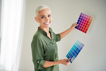 Photo of charming attractive woman dressed khaki shirt rising colors palettes indoors house...