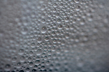 Close Up of Condensation Floating Liquid Water Bubbles and Drips on Glass from Rain
