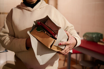Person Holding Paper Package Containing Household Items in a Domestic Setting