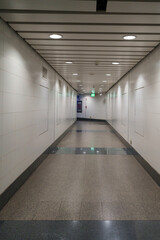 long, empty corridor with white walls and polished floors, illuminated by ceiling lights, creates serene atmosphere