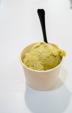 Creamy green ice cream in cup with black spoon, perfect for dessert lovers