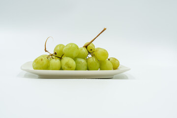Fresh green grapes on white plate, showcasing their natural beauty and vibrant color