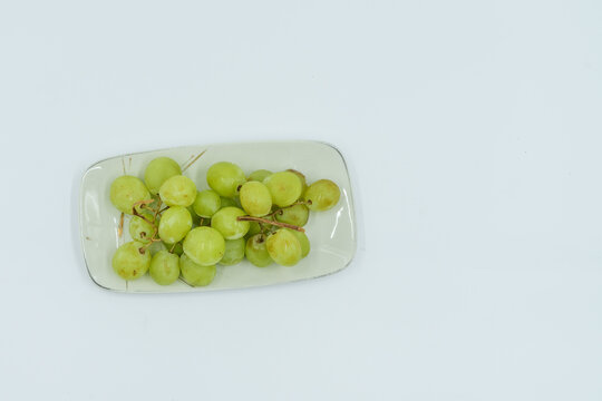 Fresh green grapes on white plate, healthy snack option, vibrant color