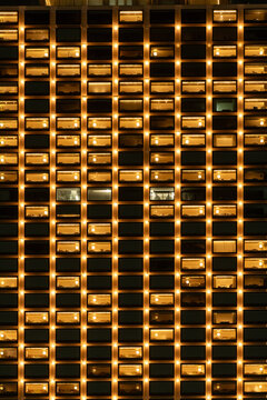 Brightly lit apartment building facade at night, showcasing illuminated windows