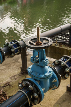 blue industrial valve on pipeline near body of water, showcasing engineering design