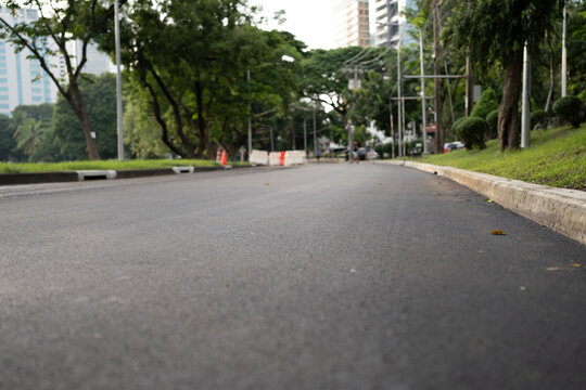 smooth asphalt road lined with trees and greenery in urban setting