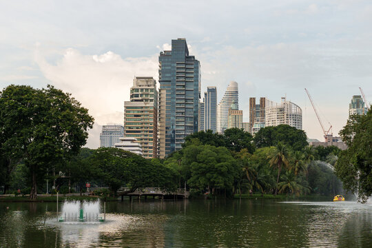 serene park view featuring modern skyscrapers, lush greenery, and tranquil lake