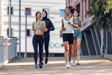 A group of four sportswomen running together through the city