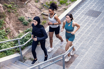 Group of three sportswomen running together through the city