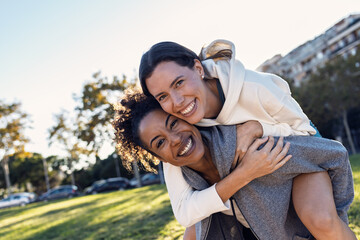 Two beautiful women having fun after running while posing at camera in the park