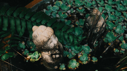 A striking statue depicting a woman stands gracefully amidst lush green plants, creating a serene and tranquil atmosphere around her
