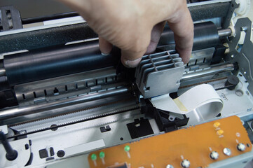 Top view of technician inspecting and repairing printer.