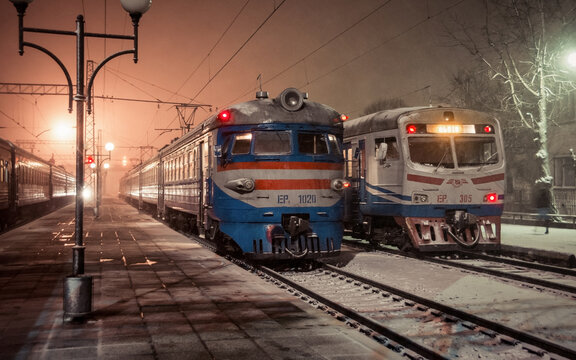 Old trains at Stryi Railway Station. Two commuter ER2 trains and night train at night, partially covered in snow. Stryi, Ukraine - April 03 2015.