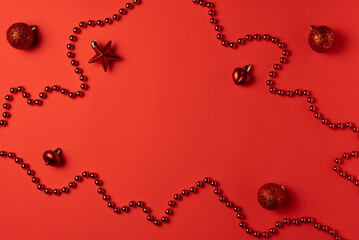Christmas red background with beads and balls. Flat lay, top view. Copy space