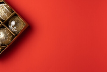 Christmas red background with box of balls. Flat lay, top view. Copy space