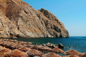 Popular Perissa beach on Santorini island with black volcanic sand near rock Mesa Vouno.