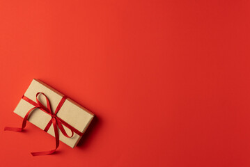 Universal red background with gift box. Flat lay, top view. Copy space