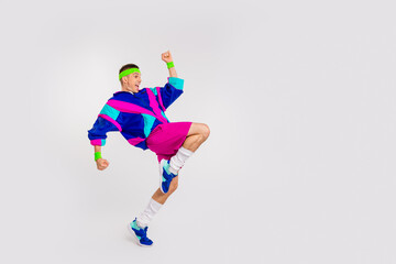 Energetic young man in vibrant retro sportswear executing a dynamic exercise on a white background, showcasing a fun and healthy lifestyle