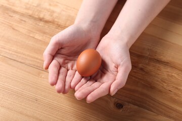 Woman with raw egg at wooden table, closeup