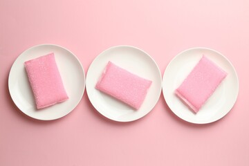 Sponges and plates on pink background, flat lay