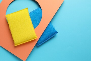 Flat lay composition with color sponges on light blue background. Space for text