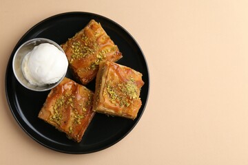 Delicious baklava with crushed nuts and ice cream on beige table, top view. Space for text