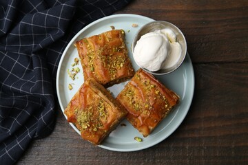 Delicious baklava with crushed nuts and ice cream on wooden table, top view