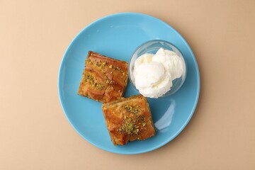 Tasty baklava with chopped nuts and scoops of ice cream on beige table, top view