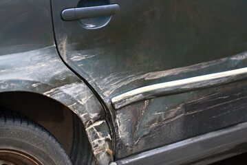 Scratches and dents on car rear fender, damaged paint after side impact. Crumpled rear fender with...