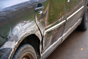 Crumpled rear fender with dents and scratches, damaged car's arch and body paint after road...
