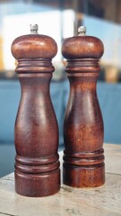 Two wooden pepper and salt grinders placed on a table with blurred background