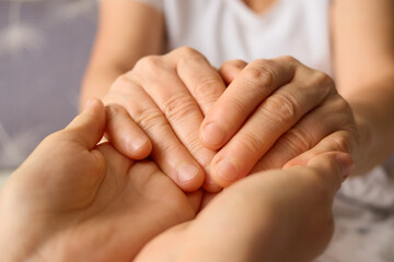 Two hands gently clasp together in a display of support and connection, highlighting intimacy and care in a calm indoor setting during a tranquil moment