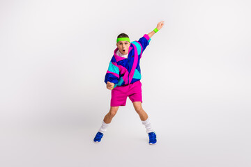 Energetic young man in bright retro sportswear performing a dynamic exercise on white background