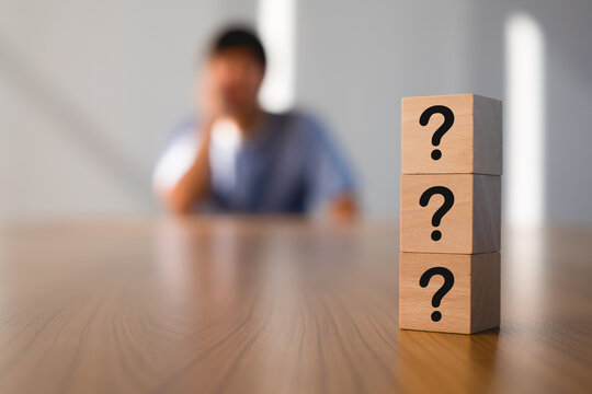 Wooden cube sign question mark symbol on wood table with man action worry, doubt and confuse. Blur motion background. thinking of problems for idea concept